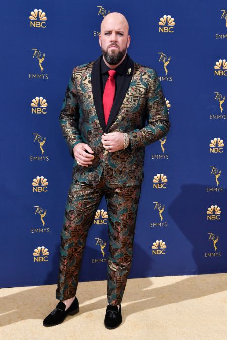 Chris Sullivan in a suit poses for a picture.